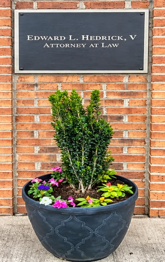 Edward L. Hedrick, V Attorney at Law sign above a potted plant at the office entrance